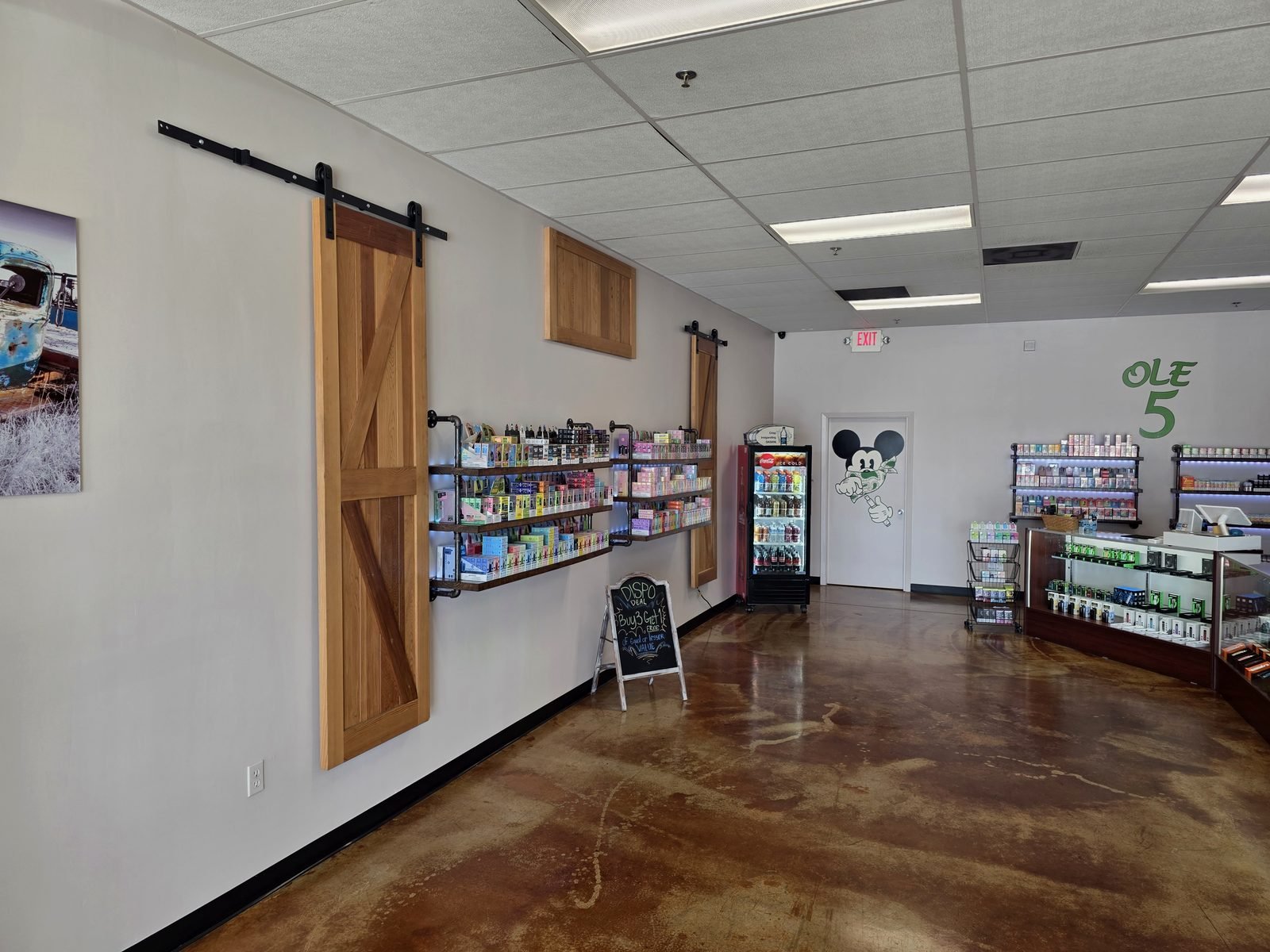 Inside Ole 5 Vapor — cedar barn doors and wall shelves stocked with disposables