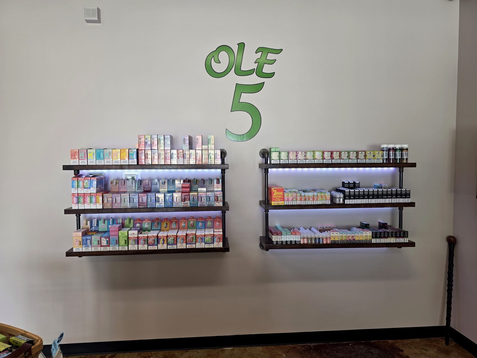 Shelves of disposables, e-liquid and salts beneath the painted Ole 5 logo